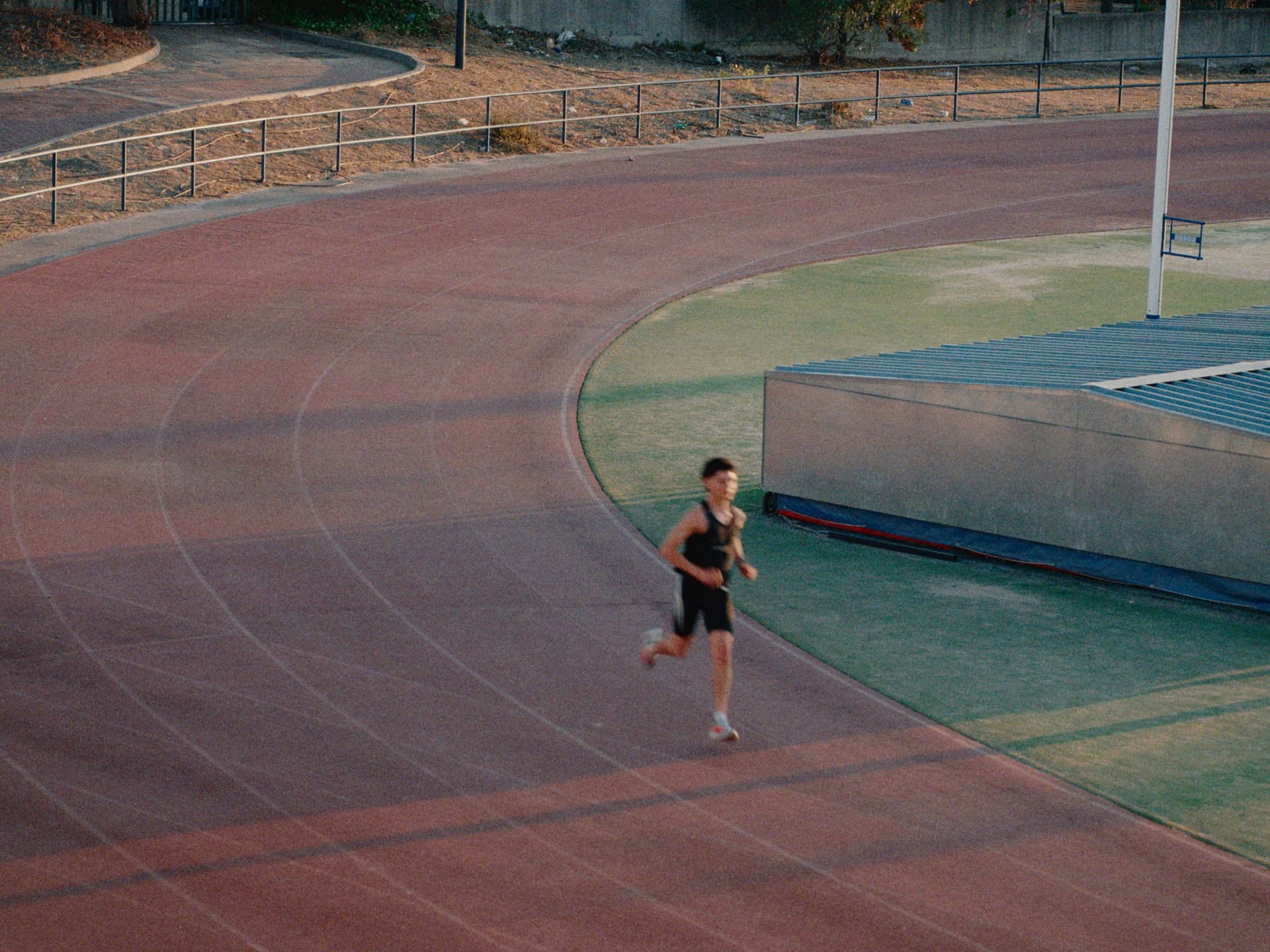 Corredor entrenando en la curva de una pista de atletismo